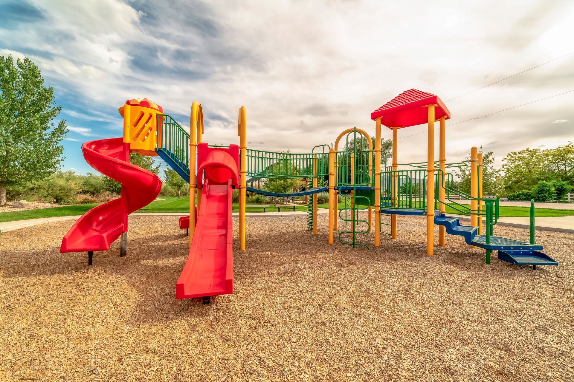 A colorful playground set in a park with a red slide.