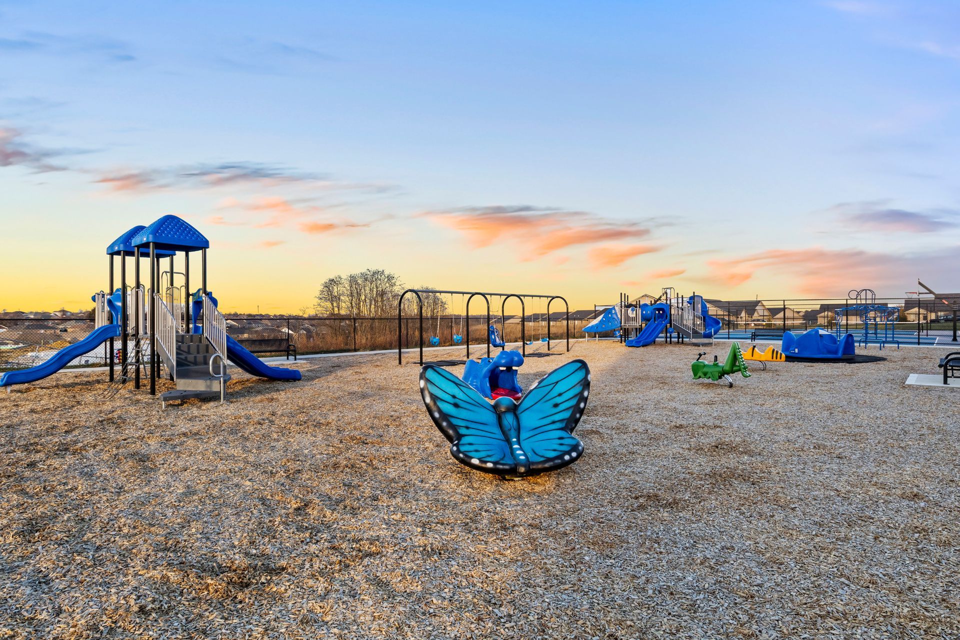 A colorful playground set in a park with a red slide.