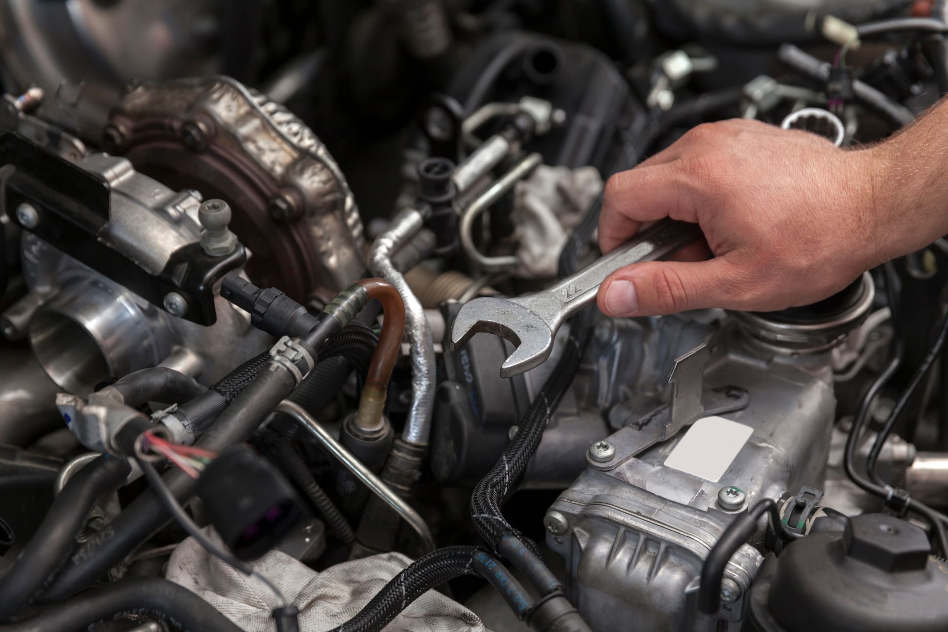 Hand inspecting a car engine bay with exposed metal parts and hoses Hand inspecting a car engine bay with exposed metal parts and hoses