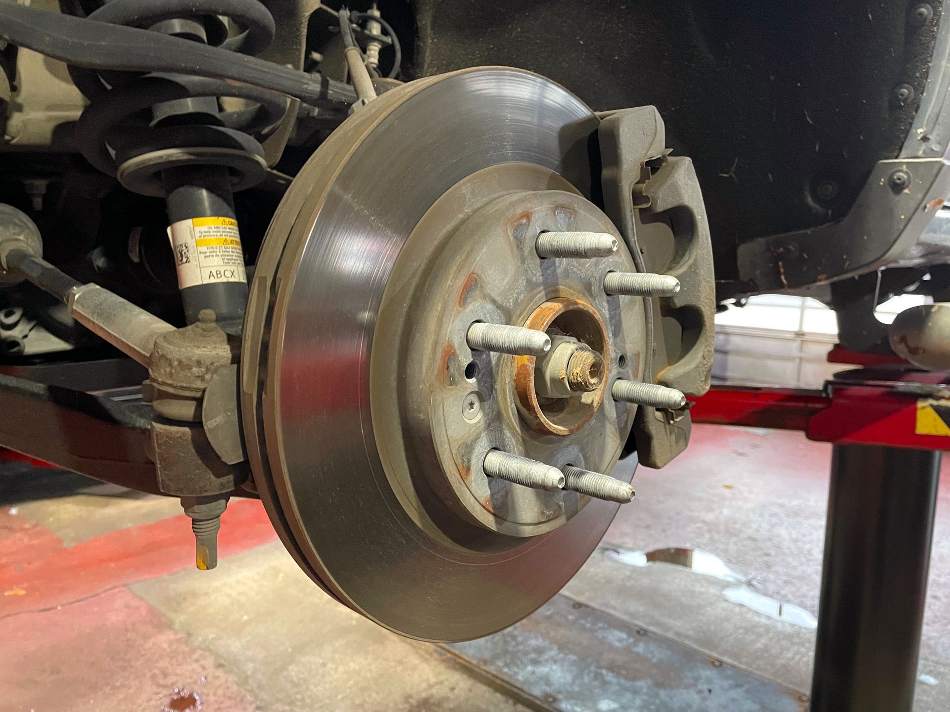 Brake rotor, caliper, and pads in great condition on a vehicle in the shop. 
