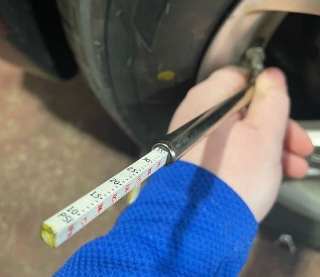 Photo of a technician checking tire pressure using a mechanical tire pressure gauge