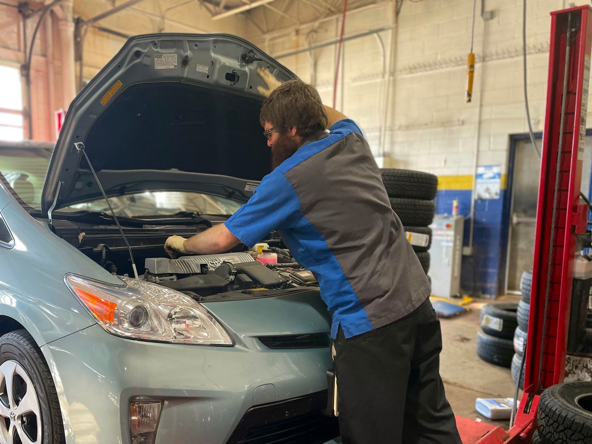 Technician checking an engine bay on a Toyota Prius during routine maintenance inspection