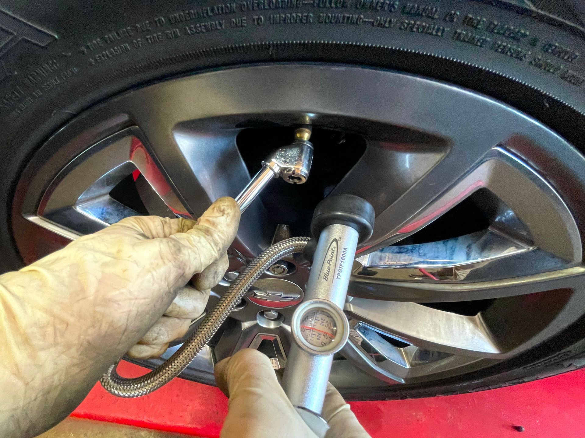 Picture of a technician checking the tire pressure on a car.