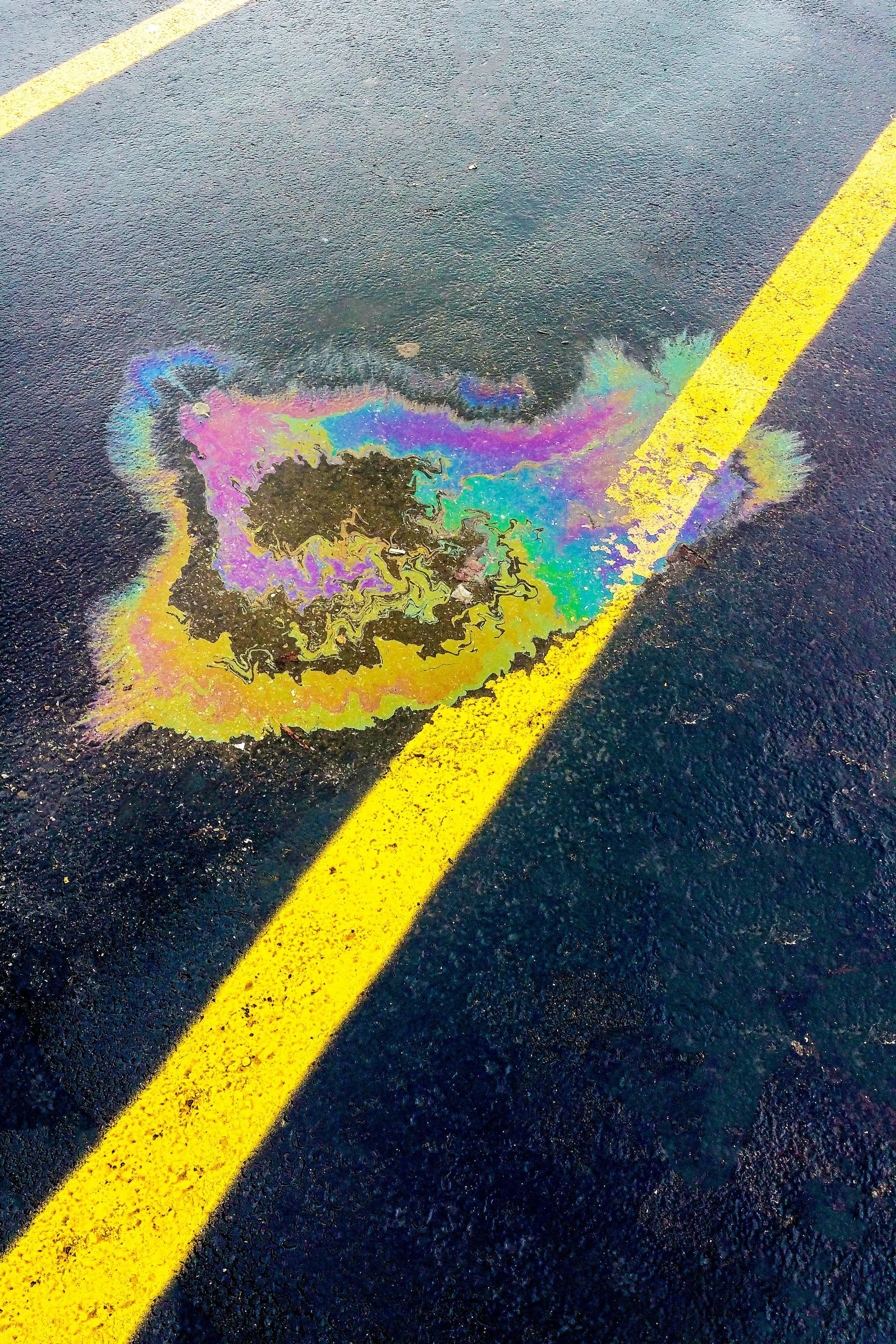 Picture of oil in a puddle in a parking lot due to an oil leak