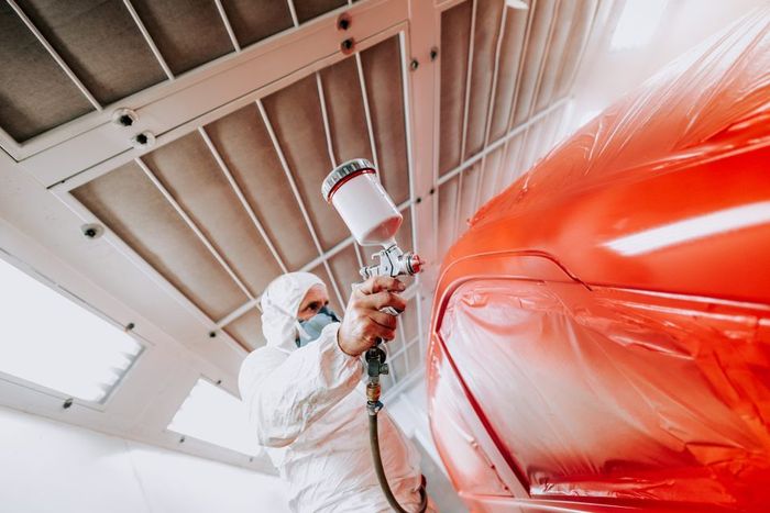 Worker sprays car paint