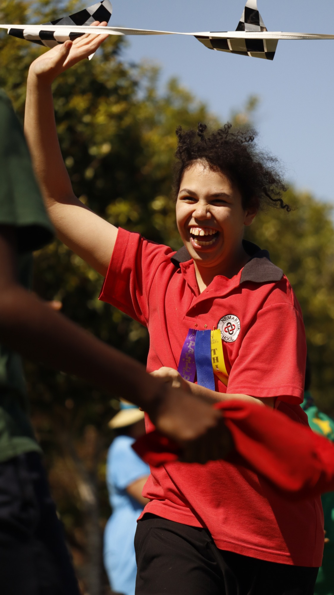 A girl in a red shirt is holding a ribbon and smiling