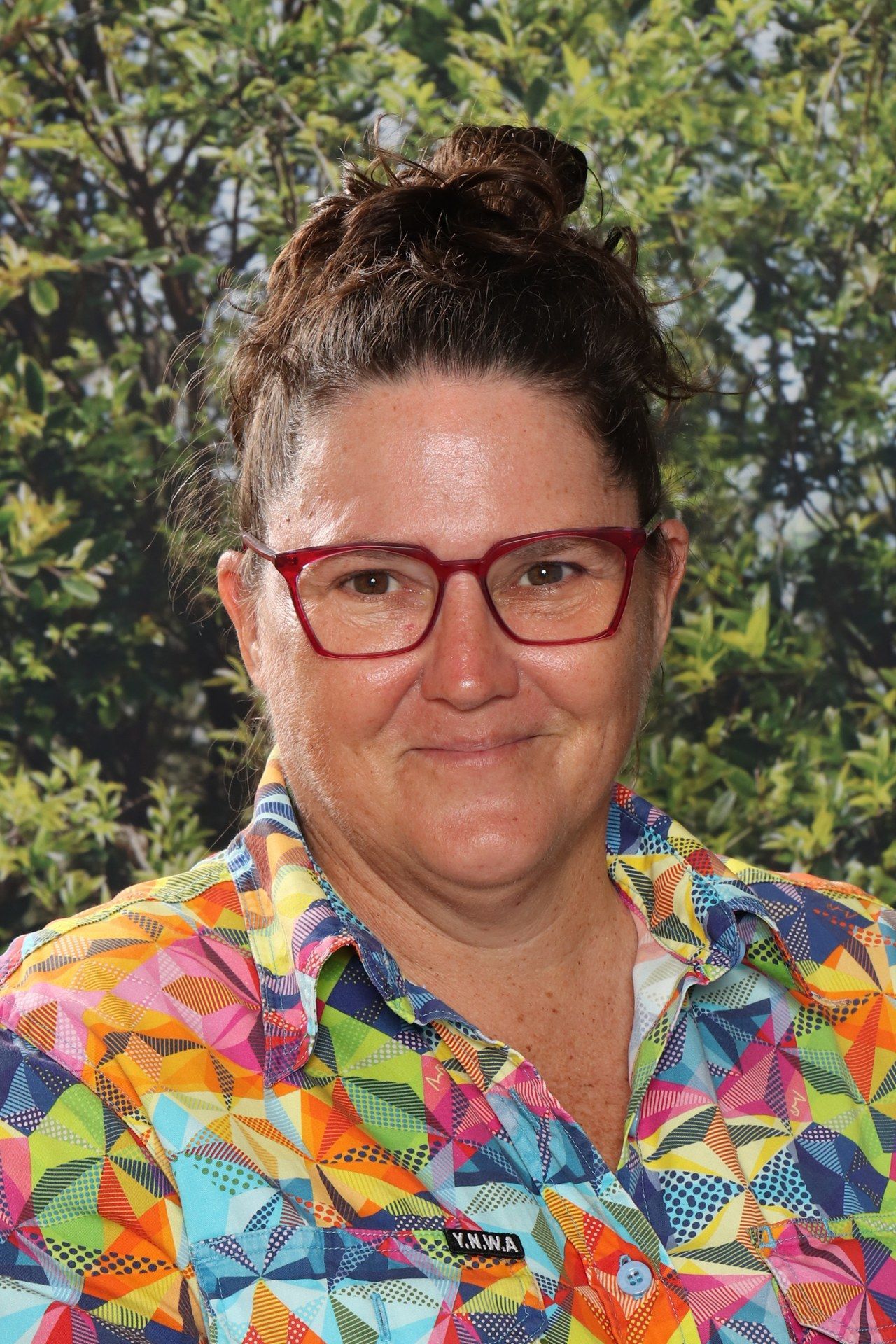 A woman wearing glasses and a blue shirt is smiling for the camera.