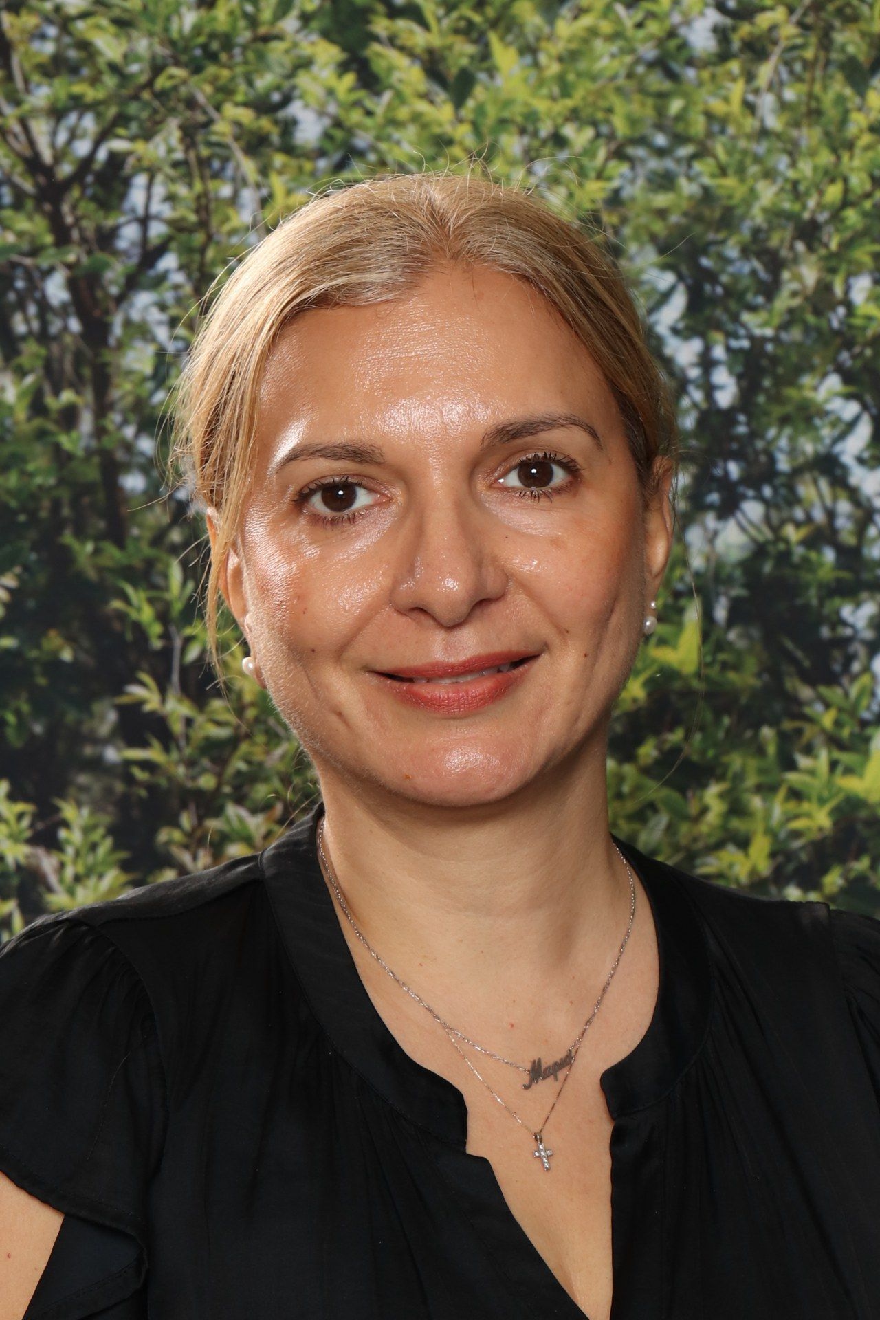 A woman in a black dress is posing for a picture in front of a blue background.