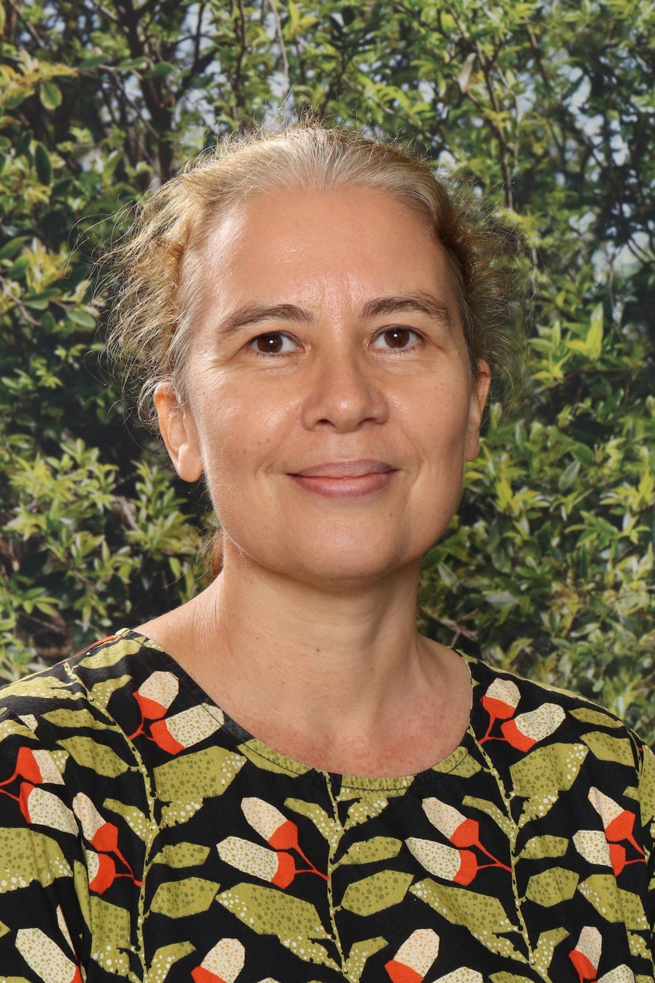 A woman in a black shirt is smiling in front of a blue background.
