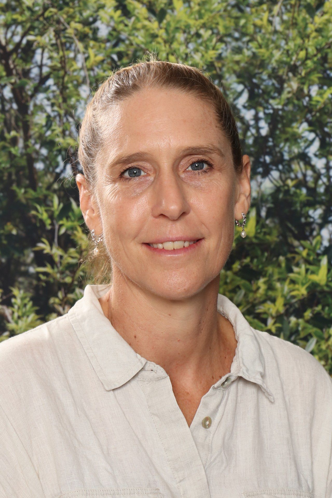 A woman with curly hair is smiling and wearing a black shirt.
