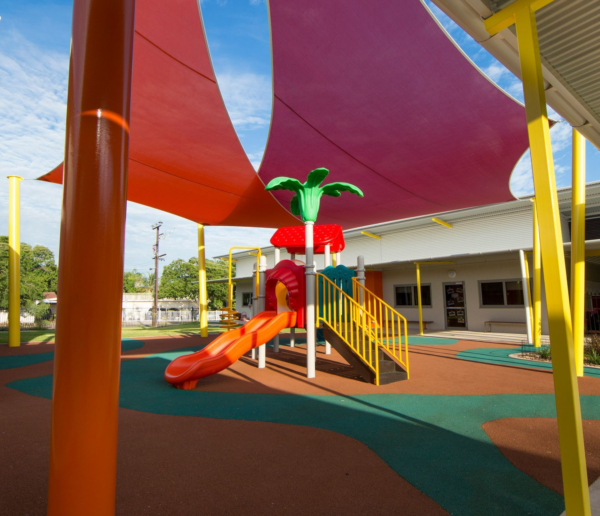 A playground with a slide and stairs under a purple umbrella