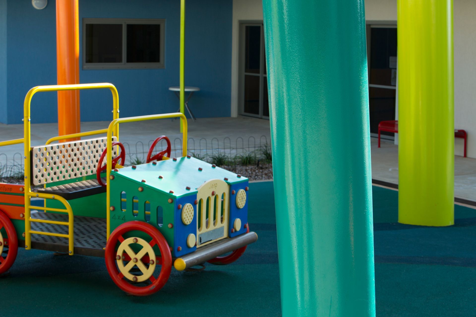 A colorful toy car is sitting in a playground