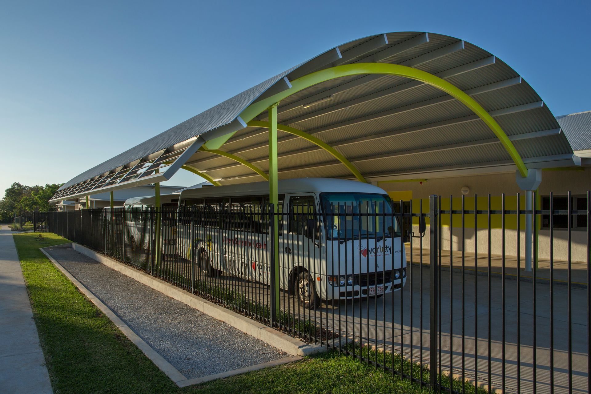 A bus is parked under a canopy in front of a building.