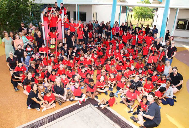 A large group of people in red shirts are posing for a picture