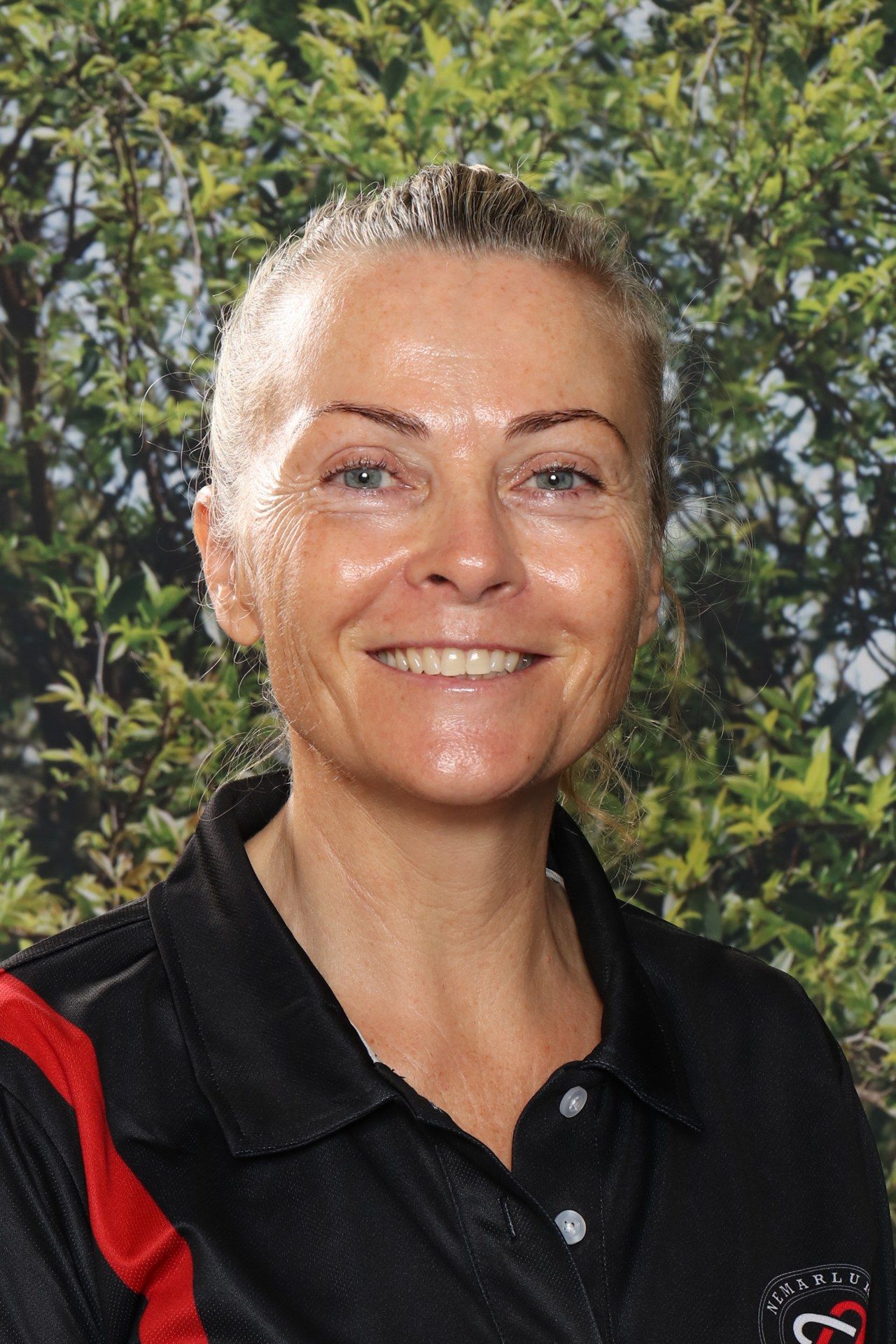 A woman in a black shirt is smiling in front of a blue background.