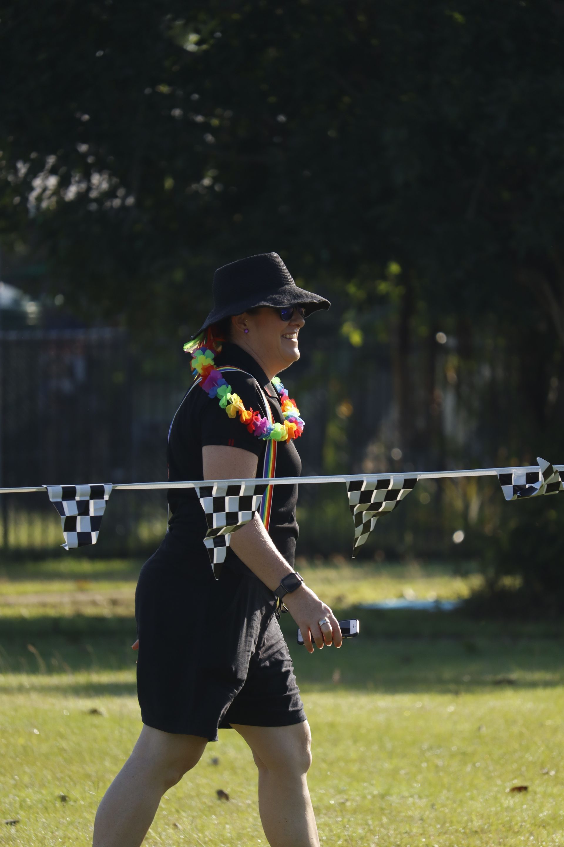 A woman wearing a lei and a hat is walking in a field with checkered flags