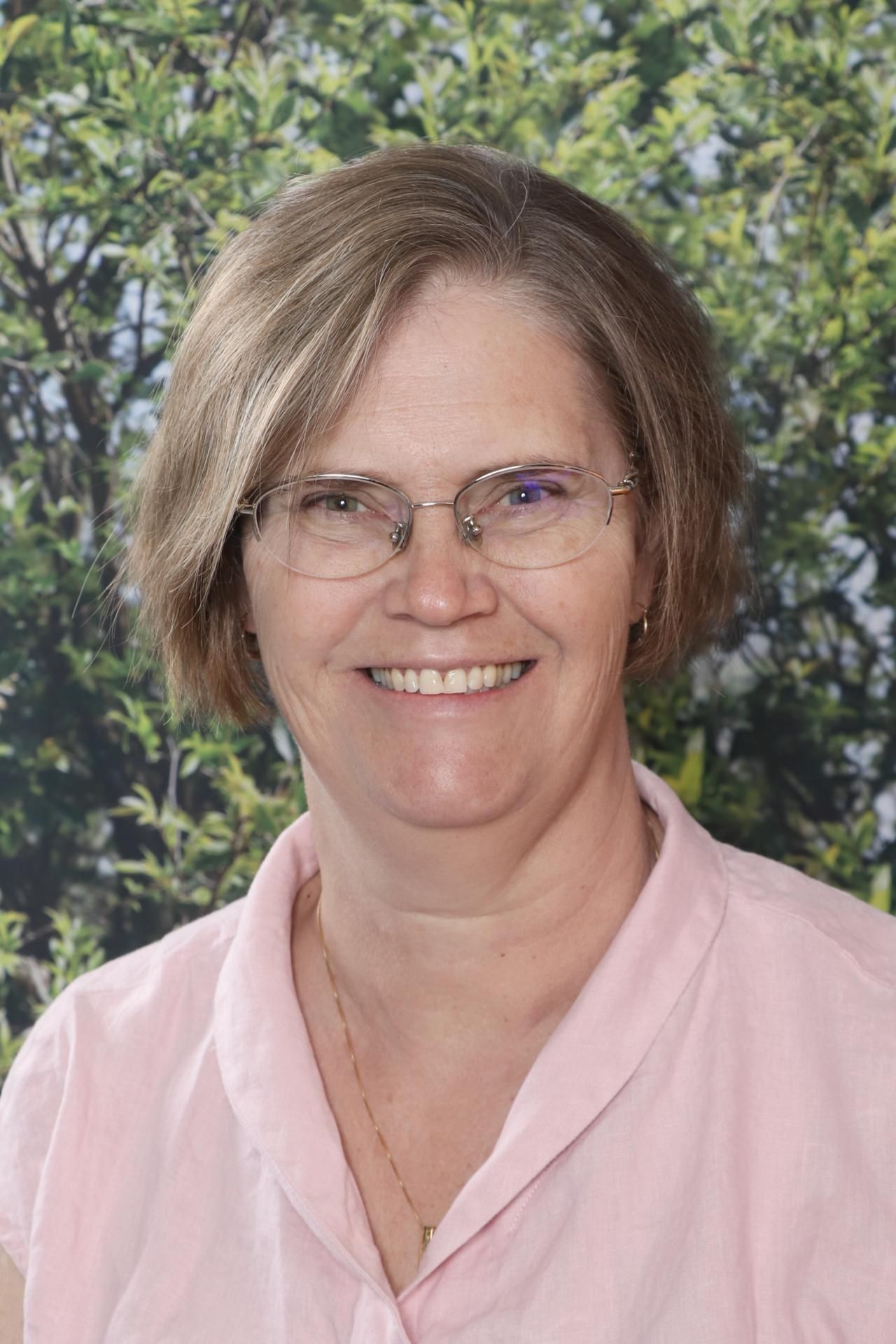 A woman wearing glasses and a red shirt is smiling for the camera.