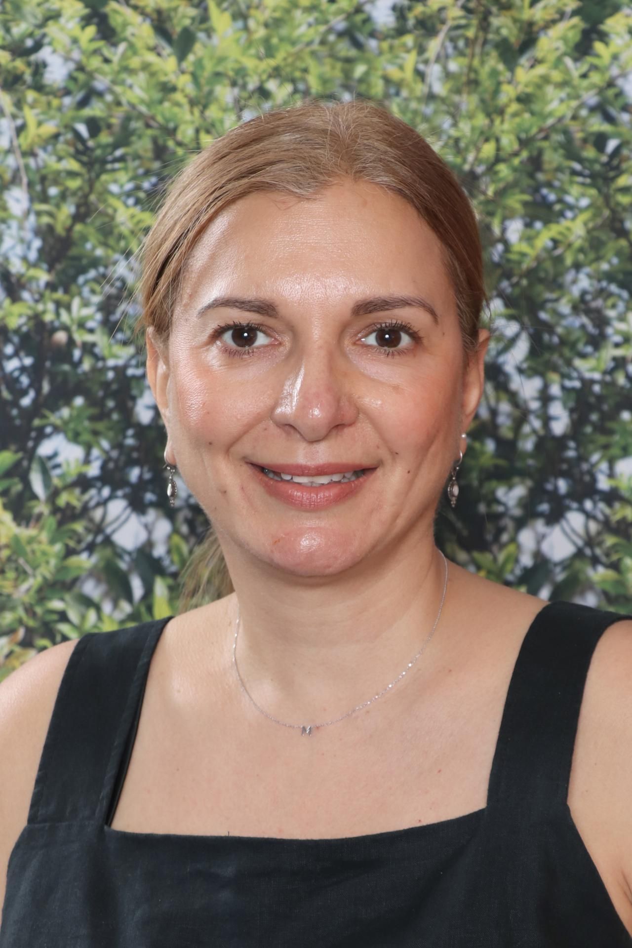 A woman in a black dress is posing for a picture in front of a blue background.