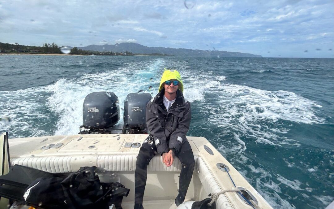 A man is sitting on the back of a boat in the ocean.