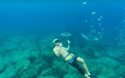 A man is swimming in the ocean without a shirt on.
