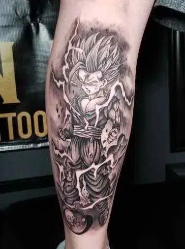 Tattoo of a character from Dragon Ball Z, with spiky hair and energy blasts, on a leg. Black and gray shading.