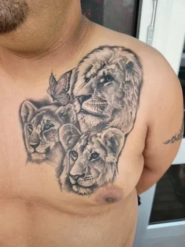 Lion family tattoo on a person's chest, featuring a lion, two lionesses, and a butterfly.