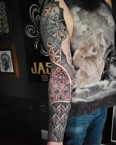 Geometric arm tattoo with shaded patterns and a central lotus flower.