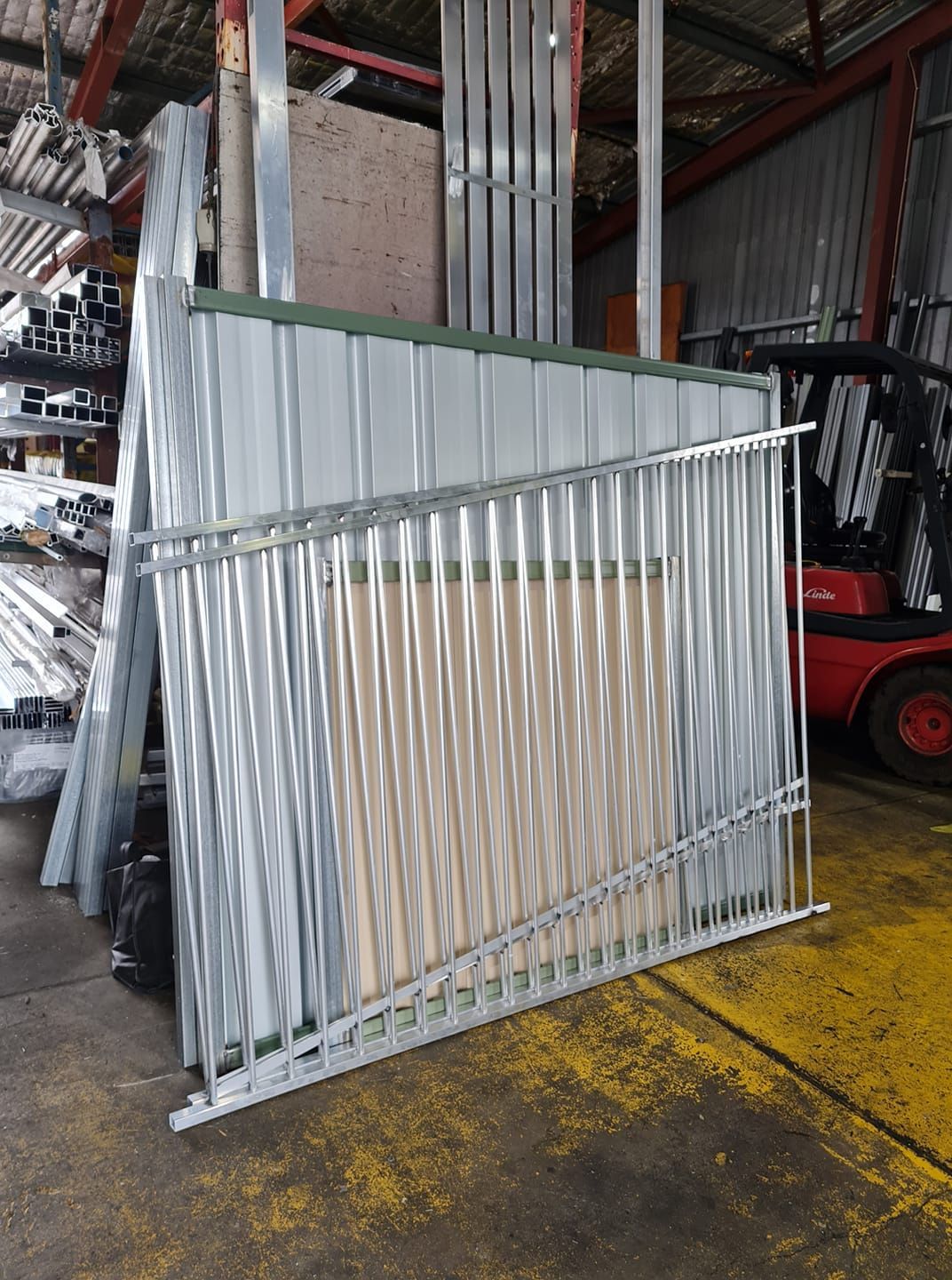 Metal Fencing and Panels Stacked in a Warehouse With a Forklift in the Background — Metal Fencing Supplies In Harrington, NSW