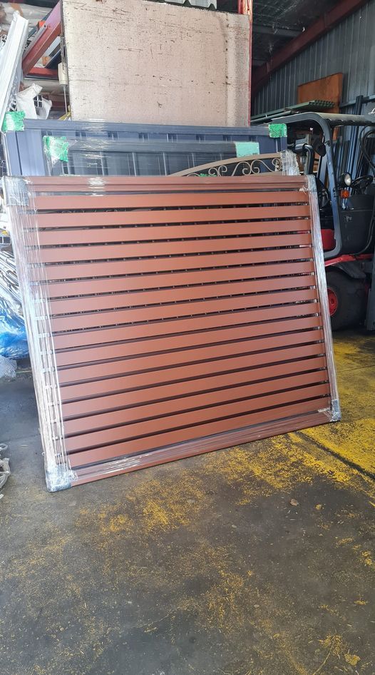 Brown Wooden Slat Panel Wrapped in Plastic, in a Warehouse Setting — Metal Fencing Supplies In Forster, NSW