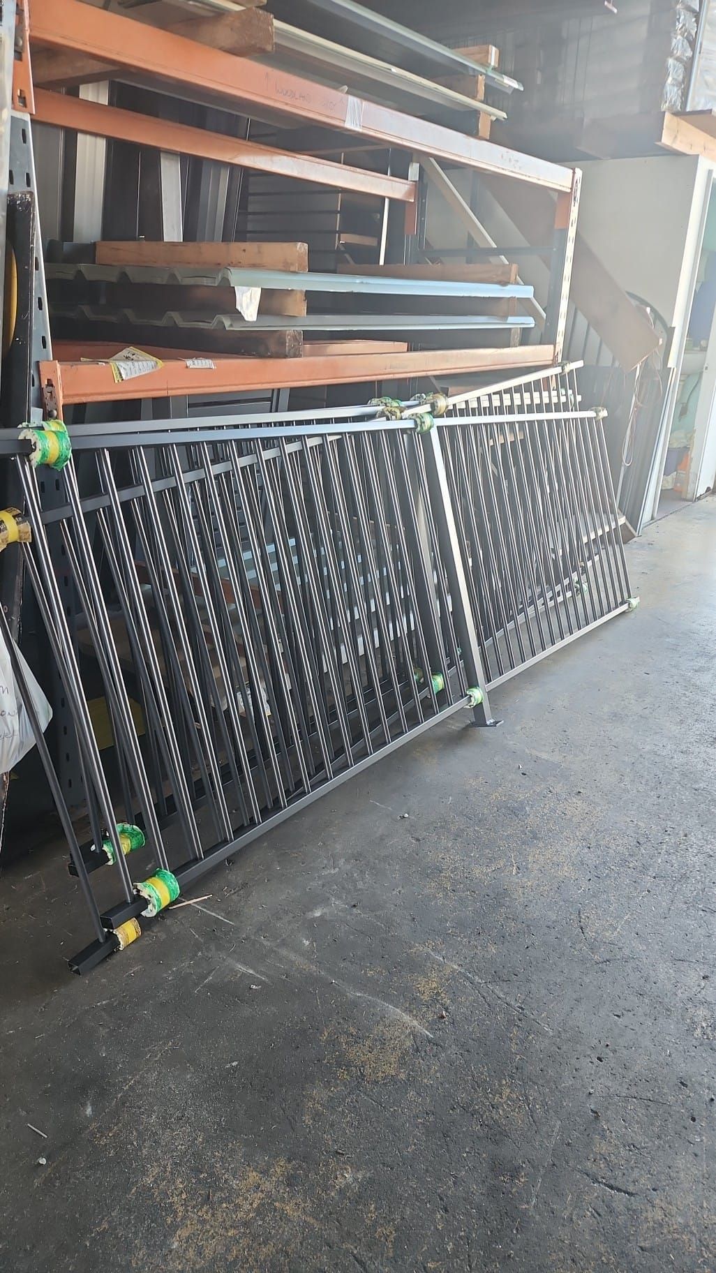 Black Metal Decorative Fence Panels Stacked Inside a Warehouse — Metal Fencing Supplies In Old Bar, NSW