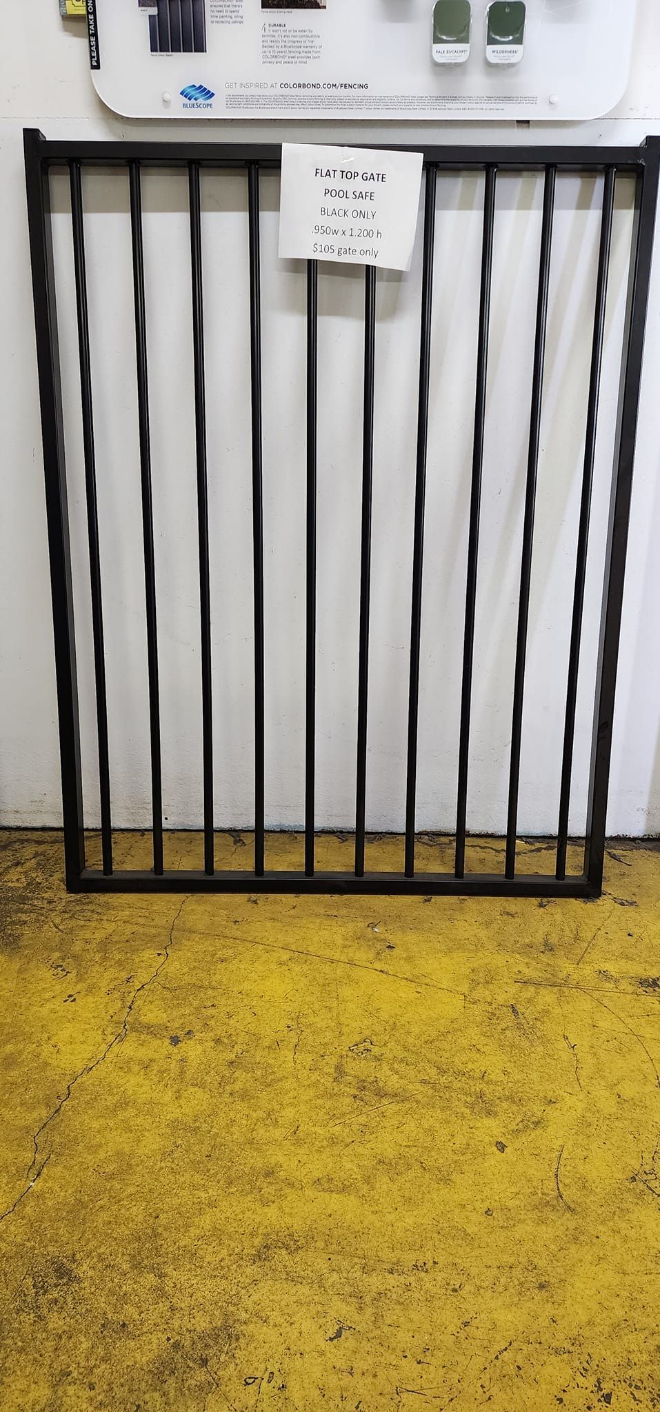Black Metal Gate Against a White Wall and Yellow Floor — Metal Fencing Supplies In Wingham, NSW