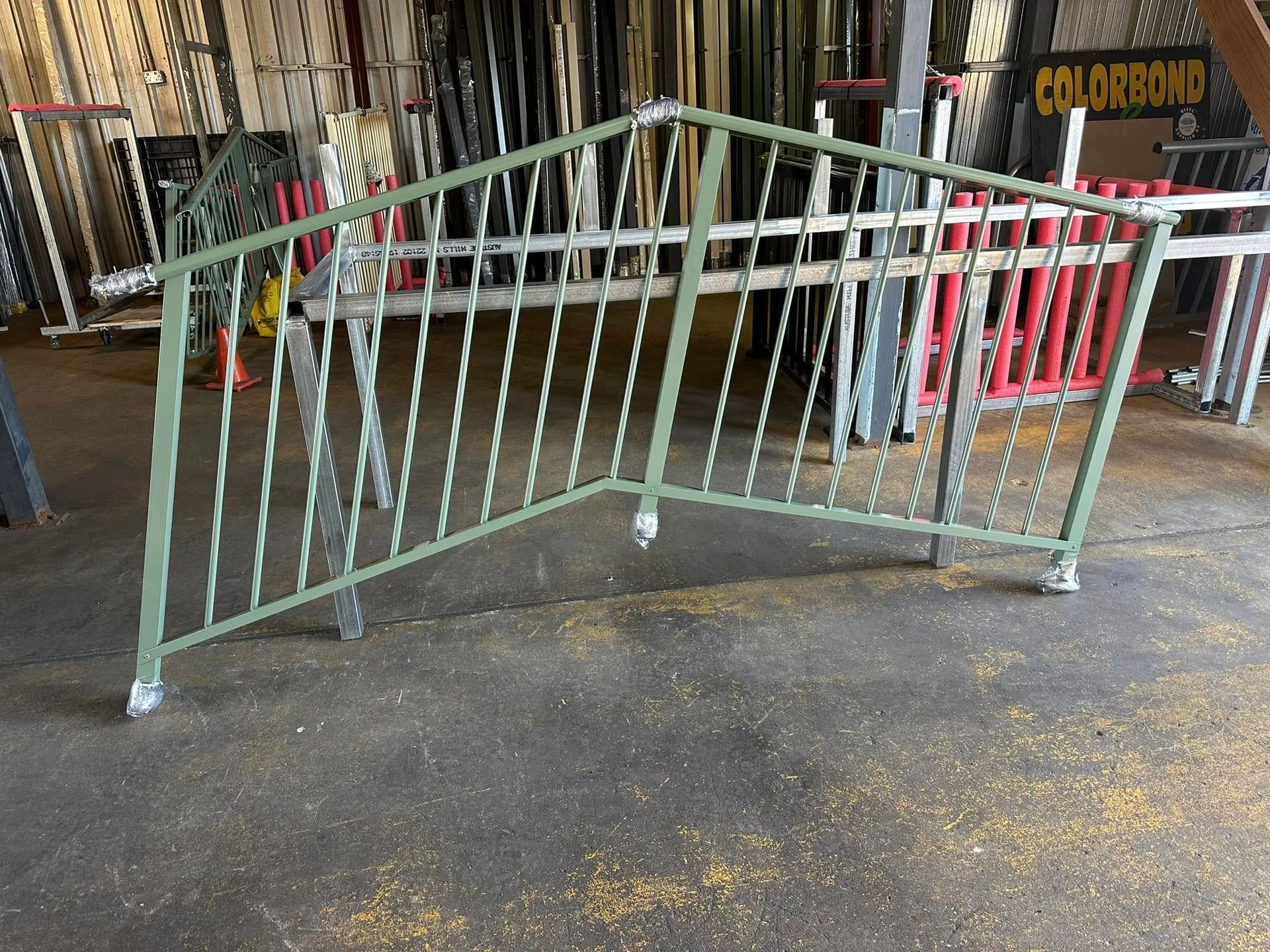 Green Metal Railing With Twisted Vertical Bars, in a Workshop Setting — Metal Fencing Supplies In Taree, NSW