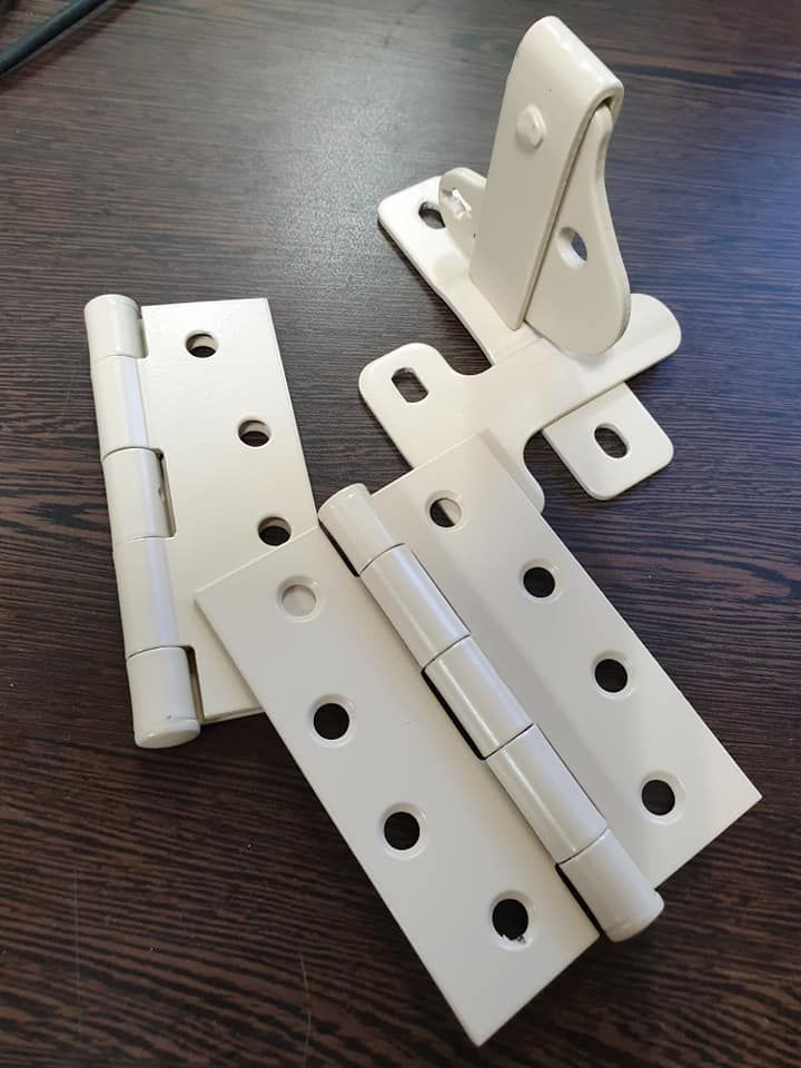 Cream-coloured Door Hinges and Latch on a Dark Brown Wooden Surface — Metal Fencing Supplies In Taree, NSW