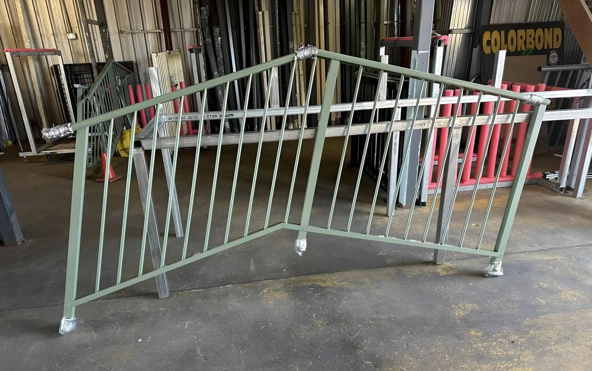 Green Metal Handrail With Twisted Spindles, on Wheels, in a Workshop — Metal Fencing Supplies In Taree, NSW