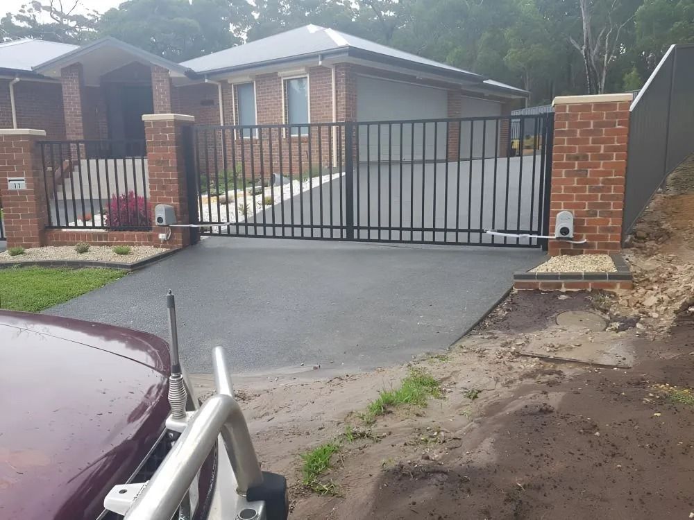 Black Wrought-iron Driveway Gate at a Brick Home — Metal Fencing Supplies In Gloucester, NSW