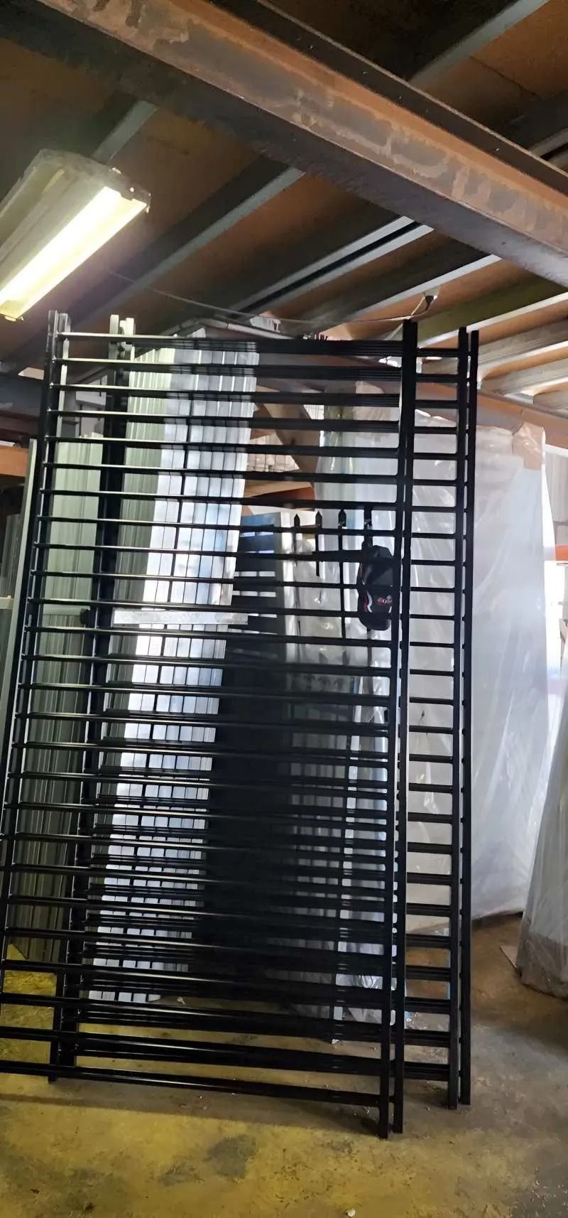 Black Metal Gates Stacked Inside a Warehouse — Metal Fencing Supplies In Taree, NSW