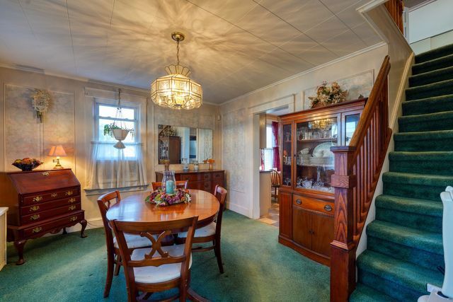 Spacious dining room interior featuring a table and chairs, with stairs leading to the second floor.