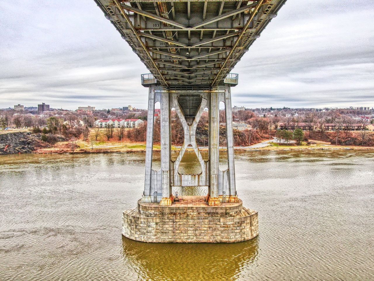 Hudson Valley Drones bridge over a river with a city in the background.
