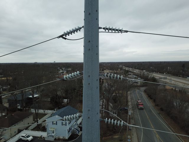 Hudson Valley Drones aerial view of a power line with a house in the background, illustrating energy distribution.