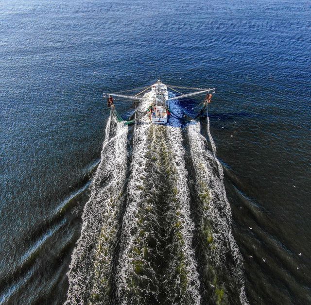 Aerial ocean photography by Hudson Valley Drones captures a stunning view of a boat floating on the ocean.