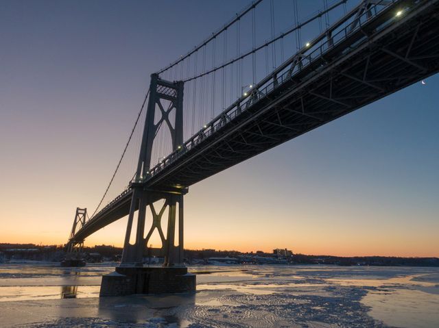 Sunset bridge photography by Hudson Valley Drones, capturing a bridge over a body of water with vibrant sunset reflections.