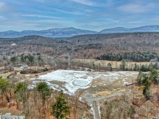 Snowy landscape photography featuring an aerial view of a snowy field with mountains in the background.