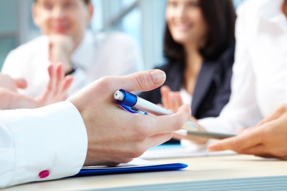 Due donne in un ufficio. Una lavora al computer portatile, l'altra legge un libro. Sullo sfondo, scaffali di libri.