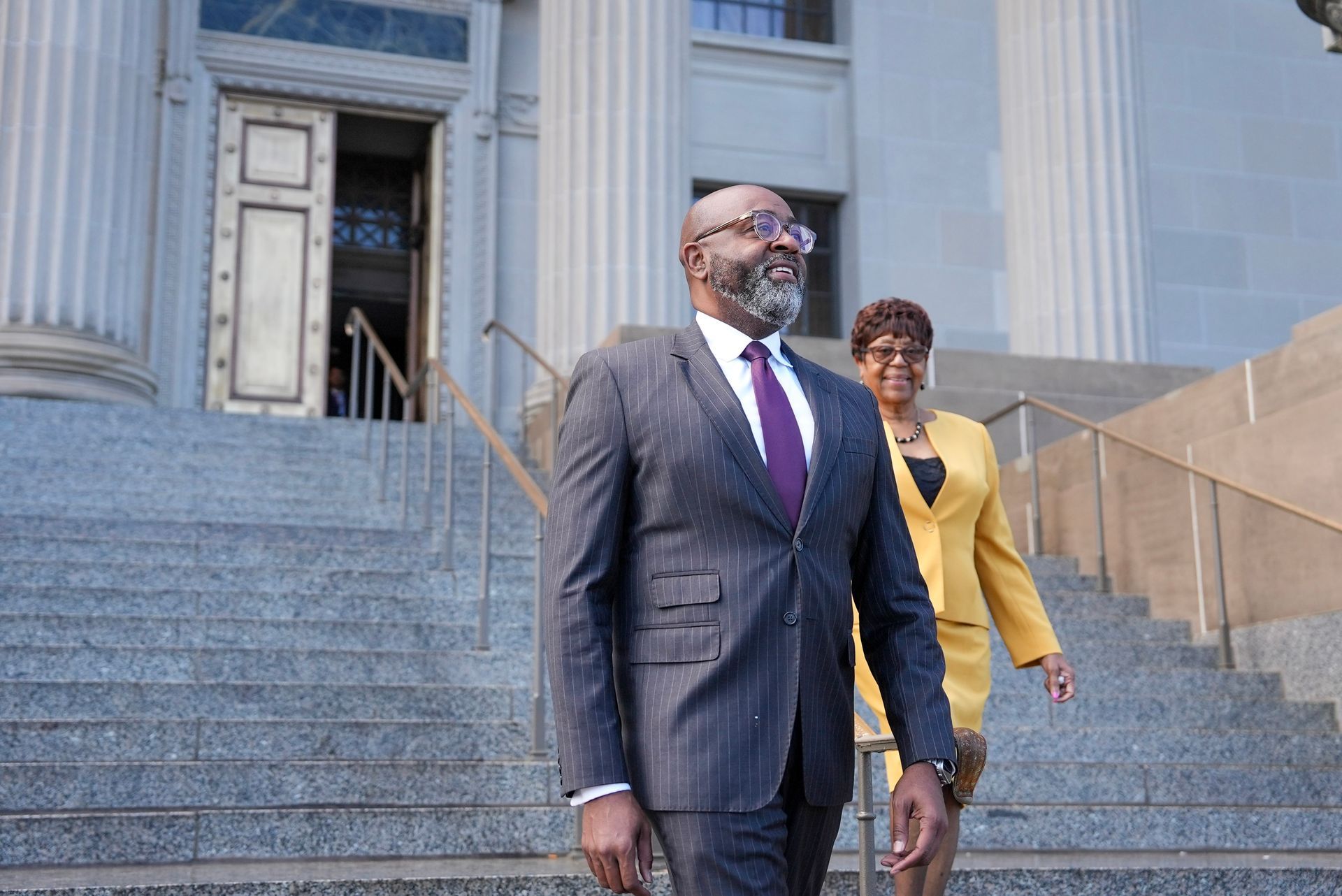 Elroy James talking to a woman in red; bike in between them. Outdoors, daytime.