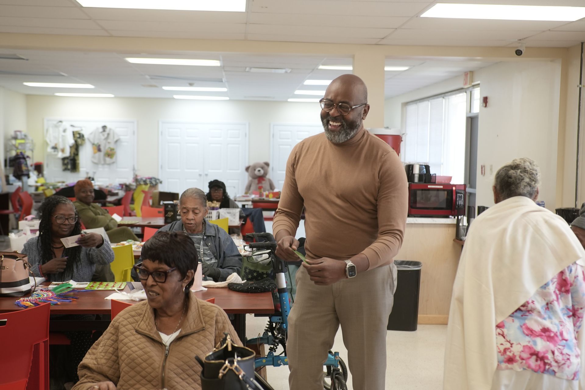 Elroy James speaks with two people at a table, discussing with a laptop.