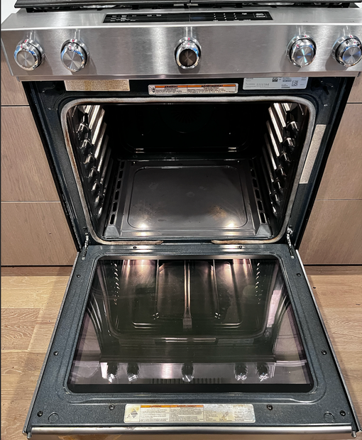 A front-view, eye-level shot of a stainless steel oven with its door open, revealing the empty interior.