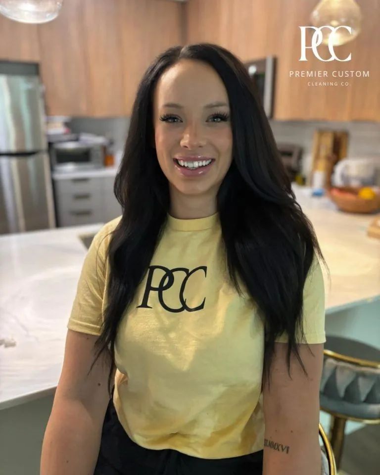 A hand in a yellow rubber glove wipes a white countertop in a tiled bathroom.