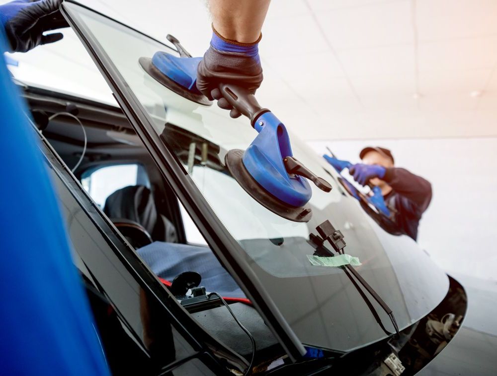 A Man is Installing a Windshield on a Car — Bendigo Windscreens In Bendigo, VIC