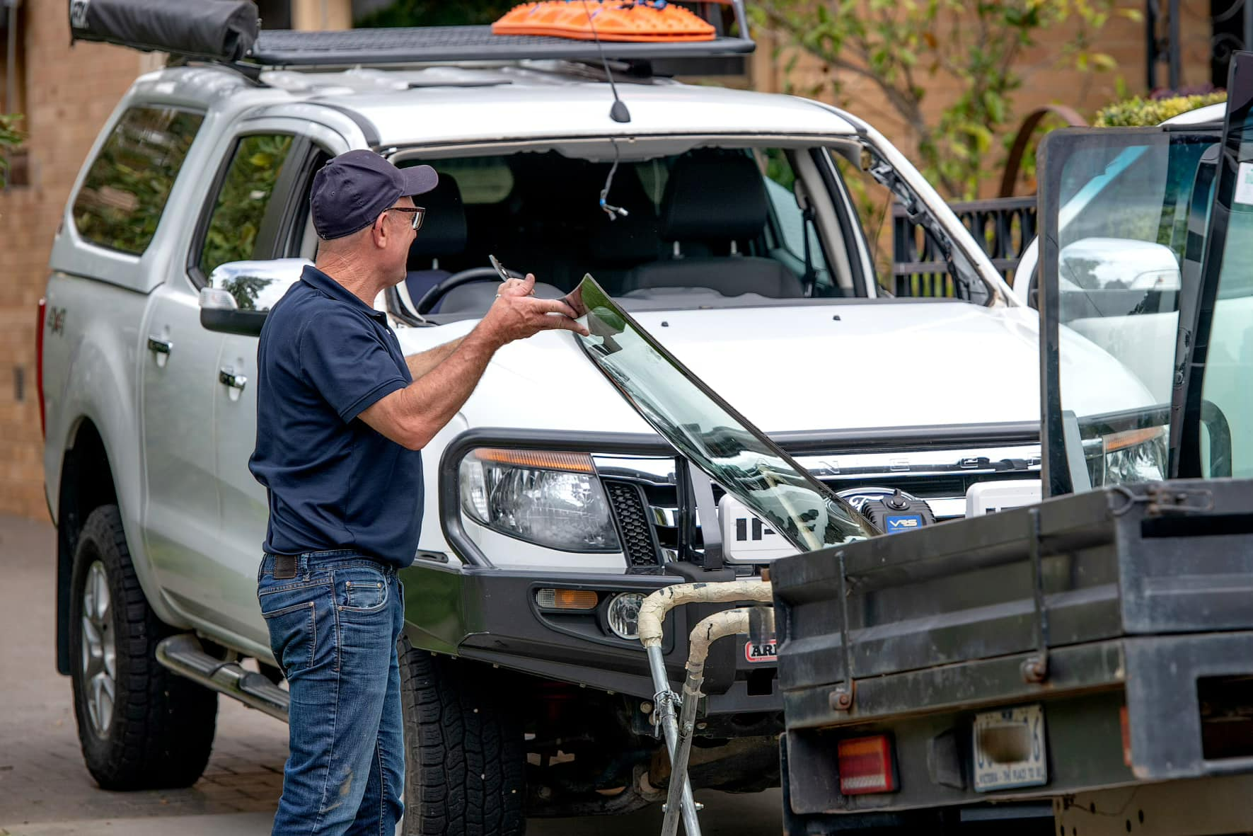 A Man Is Fixing A Windshield On A White Truck — Bendigo Windscreens in Bendigo, VIC