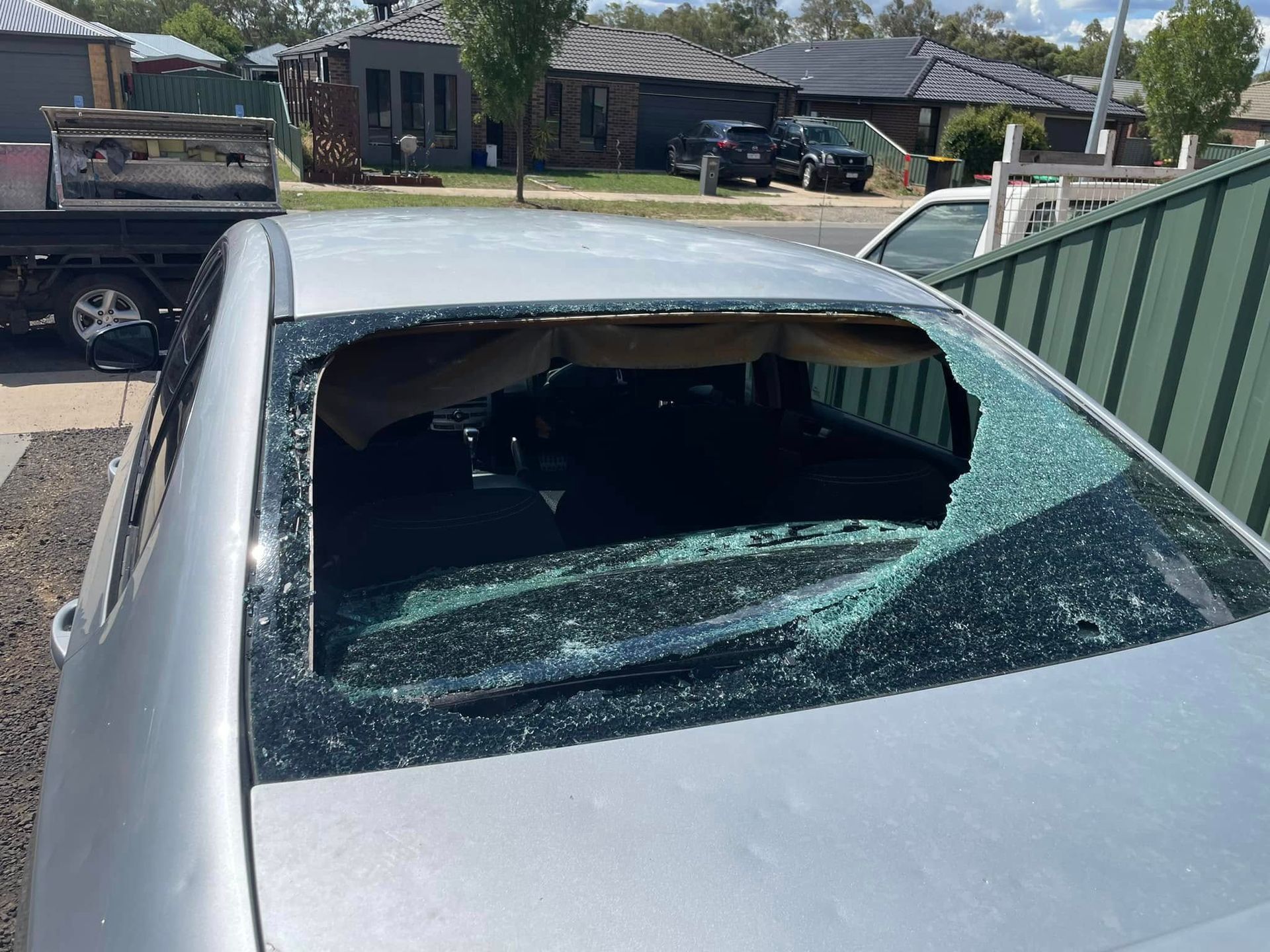 A Silver Car With a Broken Windshield is Parked in a Driveway — Bendigo Windscreens In Bendigo, VIC